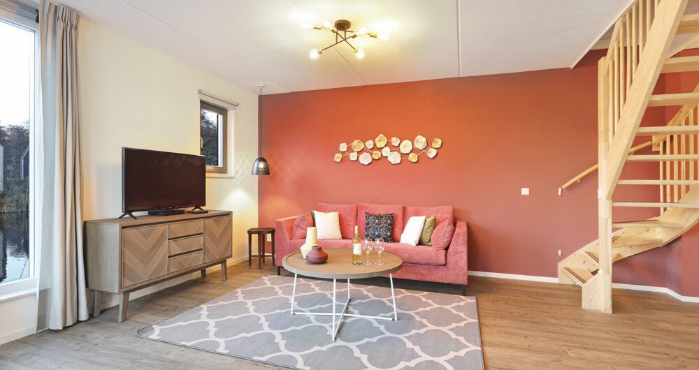 Woonkamer met tomatenrode achterwand in de woonkamer in een van de vakantiehuizen van Landal