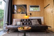 Zithoek met leren bank voor het wandgrote raam in het tiny house