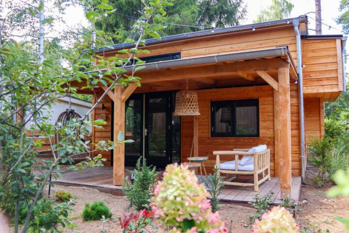Overdekt terras met een hangstoel, bij een tiny house in Beekbergen