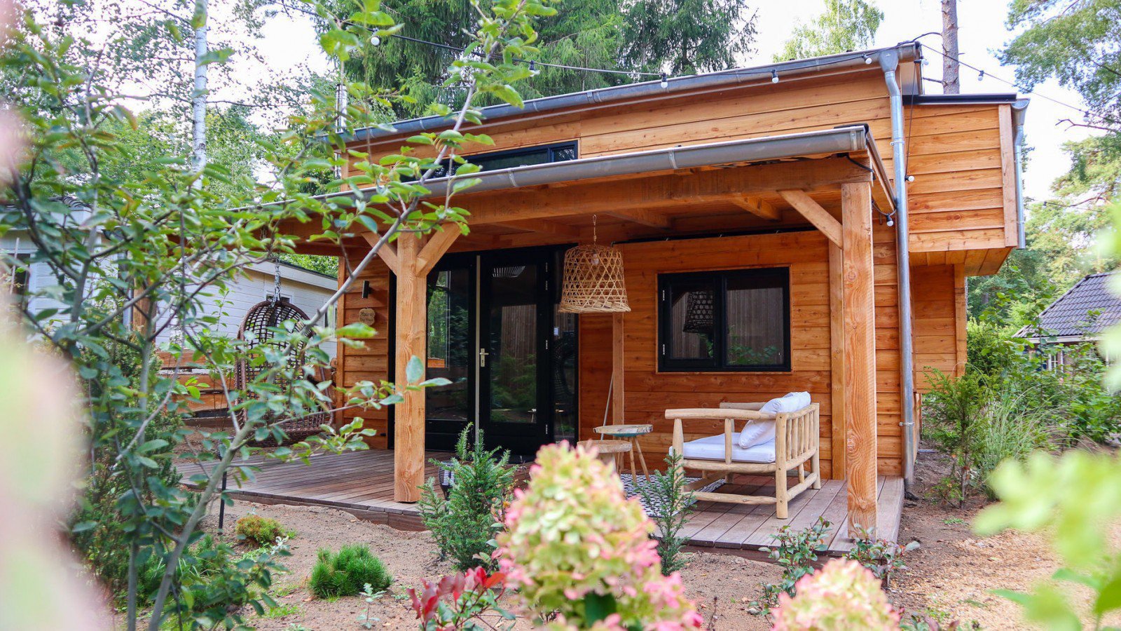 Overdekt terras met een hangstoel, bij een tiny house in Beekbergen