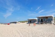 Strand met spelende kinderen en strandhuisjes