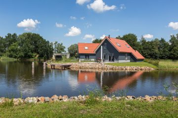 Grijze vakantiehuizen met oranje daken aan de waterkant,