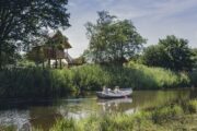 Bootje op rivier de Regge met op de achtergrond 2 boomhutten