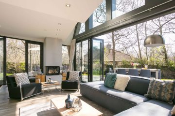 Grote woonkamer met zonlicht en een grote open schuifpui