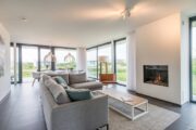 Lichte woonkamer met sfeerhaard en grote ramen in de Z'AND villa