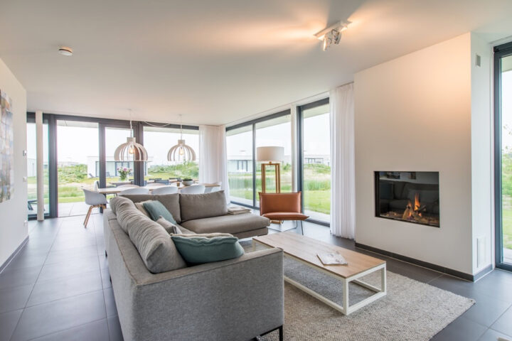 Lichte woonkamer met sfeerhaard en grote ramen in de Z'AND villa